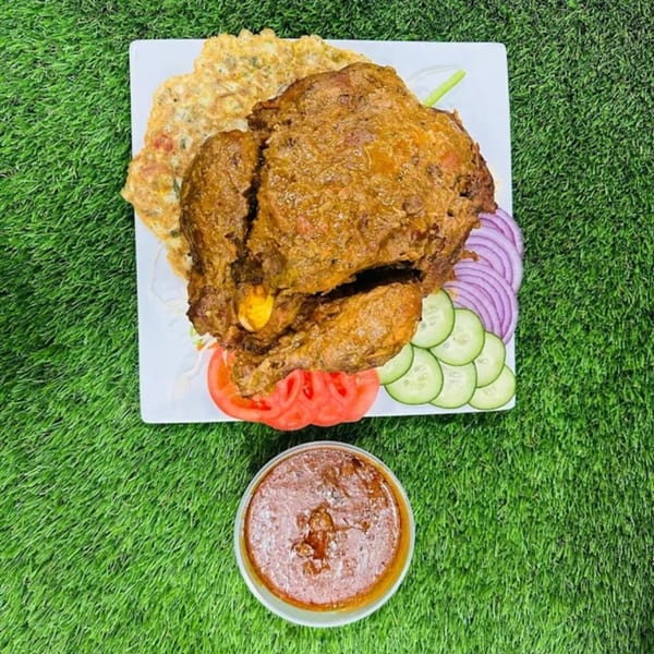 Indian chicken curry with omelet, sliced onions, cucumbers, tomatoes, and a side of sauce.