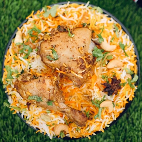 Little Spice Indian Cuisine's chicken biryani with rice, cashews, and star anise on a green background.