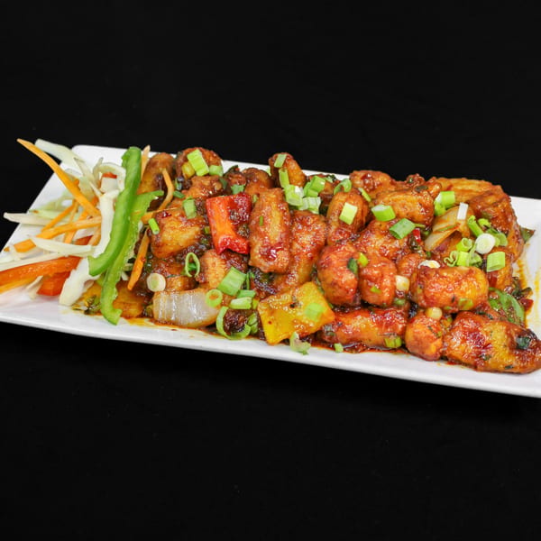 Chilli Paneer from Little Spice Indian Cuisine, garnished with spring onions and a side salad.